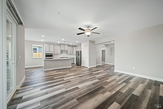 unfurnished living room featuring recessed lighting, light wood-type flooring, a ceiling fan, and baseboards