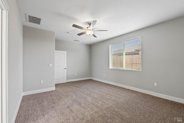 empty room with baseboards, visible vents, carpet, and ceiling fan