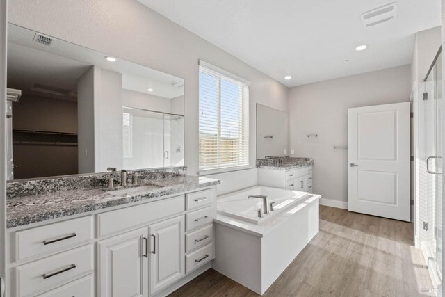 bathroom with wood finished floors, visible vents, a sink, and a shower stall