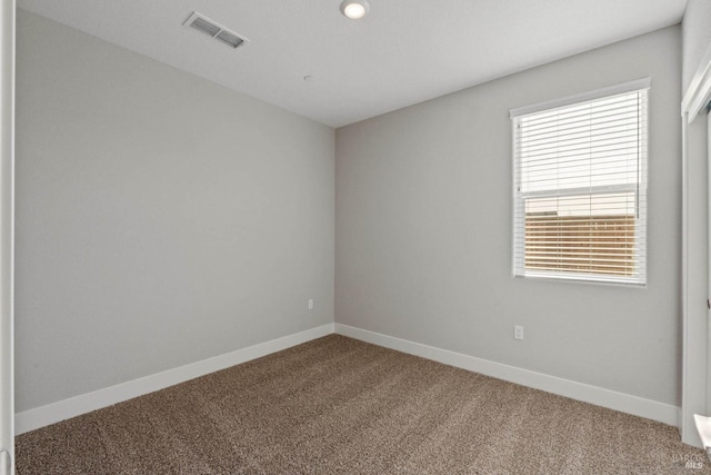 unfurnished room with carpet floors, visible vents, and baseboards