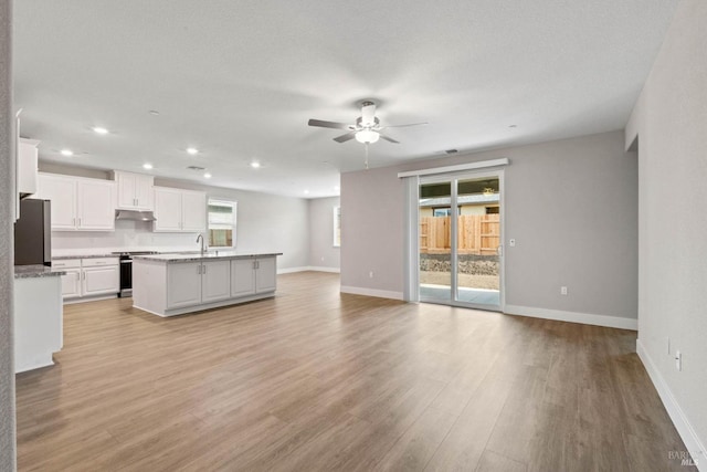 unfurnished living room featuring recessed lighting, light wood finished floors, a ceiling fan, and a sink
