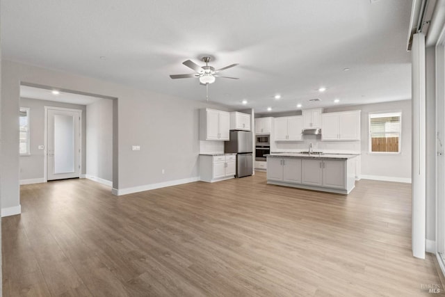 kitchen with ceiling fan, baseboards, appliances with stainless steel finishes, and light wood-style flooring