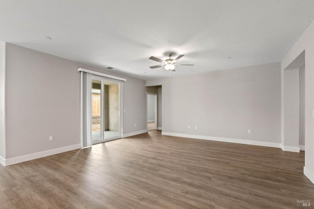 empty room featuring wood finished floors, baseboards, and ceiling fan