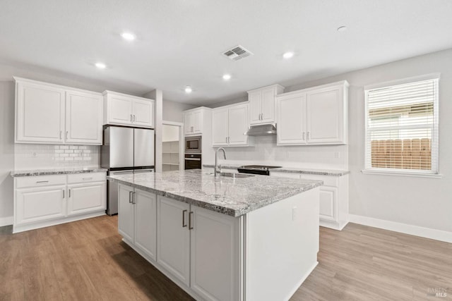 kitchen with stainless steel appliances, a sink, visible vents, baseboards, and under cabinet range hood
