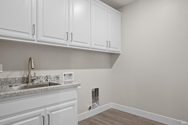 laundry room featuring a sink, baseboards, light wood-style flooring, cabinet space, and washer hookup