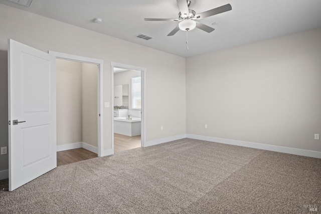 unfurnished bedroom with ensuite bathroom, baseboards, visible vents, carpet, and ceiling fan