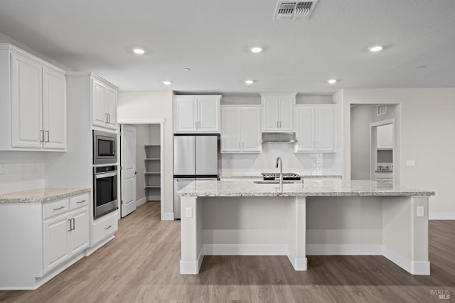 kitchen featuring under cabinet range hood, light wood finished floors, stainless steel appliances, and visible vents