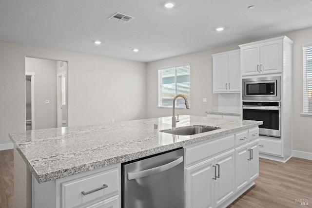 kitchen featuring a kitchen island with sink, a sink, visible vents, light wood-style floors, and appliances with stainless steel finishes