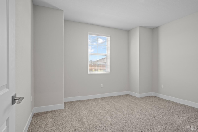 unfurnished room featuring light carpet and baseboards