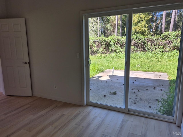 doorway with baseboards and light wood-style floors