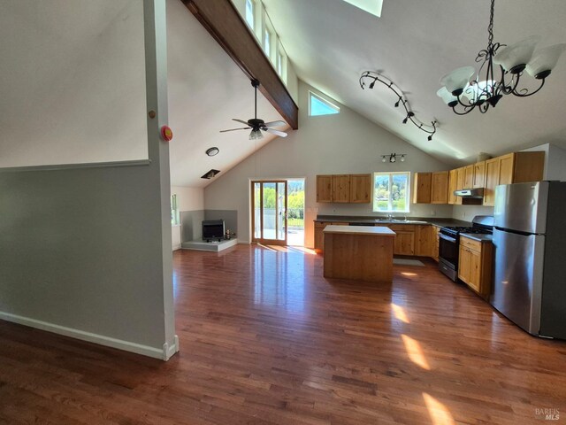 kitchen with beam ceiling, open floor plan, baseboards, a kitchen island, and appliances with stainless steel finishes