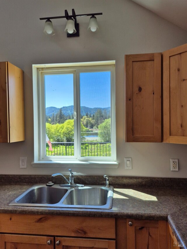 kitchen with brown cabinetry, dark countertops, and a sink