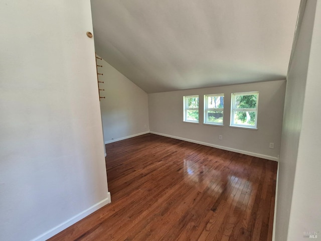 additional living space with lofted ceiling, dark wood-type flooring, and baseboards