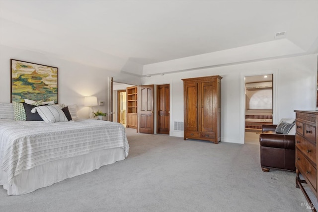 bedroom with ensuite bathroom, visible vents, and light colored carpet