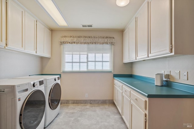 laundry room featuring washing machine and clothes dryer, visible vents, and cabinet space