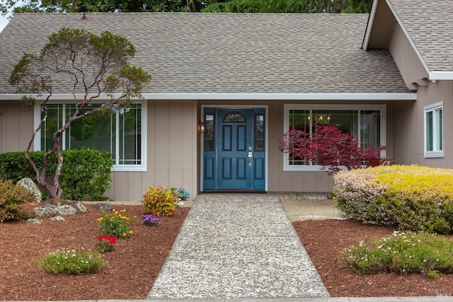 view of exterior entry with roof with shingles