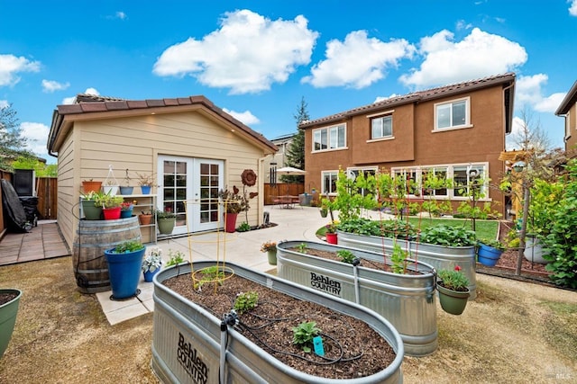 rear view of house featuring a patio, fence, french doors, and a garden
