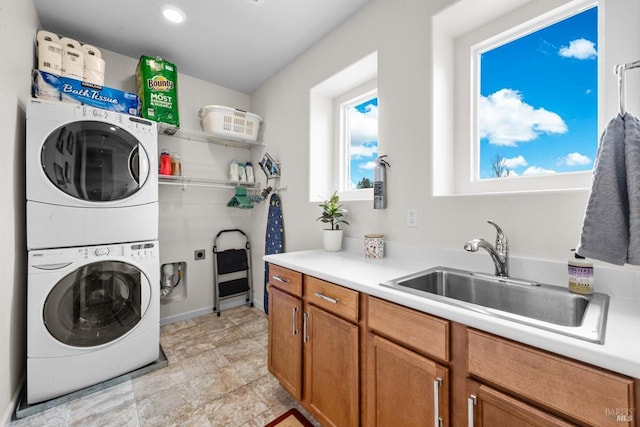 laundry room featuring stacked washer and dryer, recessed lighting, cabinet space, and a sink