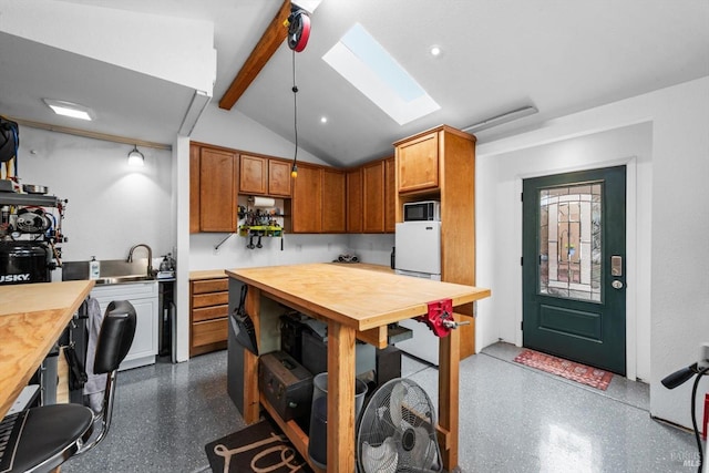 kitchen with dark speckled floor, open shelves, brown cabinetry, and vaulted ceiling with skylight