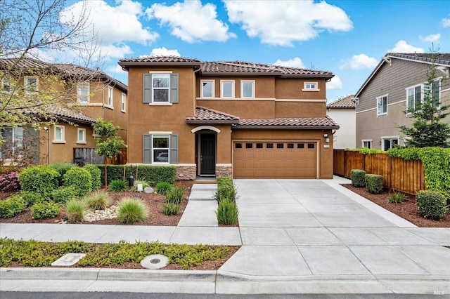 mediterranean / spanish home with fence, concrete driveway, a tile roof, an attached garage, and stucco siding