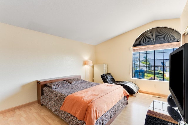 bedroom with baseboards, vaulted ceiling, and wood finished floors