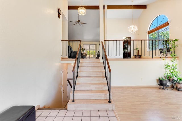 stairway with an inviting chandelier, wood finished floors, high vaulted ceiling, and beamed ceiling
