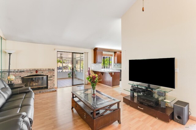 living area featuring a brick fireplace and light wood-style flooring