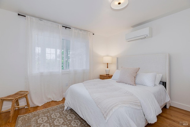 bedroom with wood finished floors and a wall mounted AC
