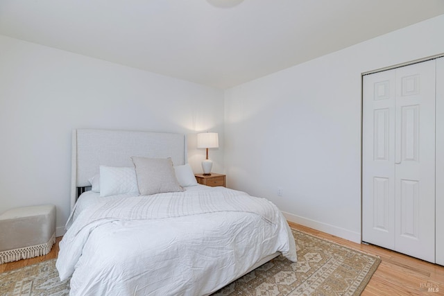 bedroom featuring baseboards, light wood-style floors, and a closet