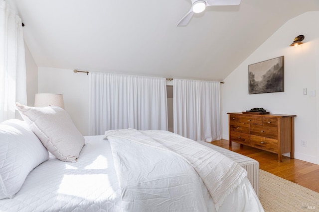 bedroom with vaulted ceiling, wood finished floors, baseboards, and ceiling fan