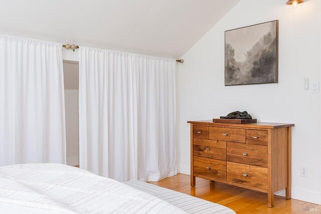 bedroom with vaulted ceiling and light wood-type flooring