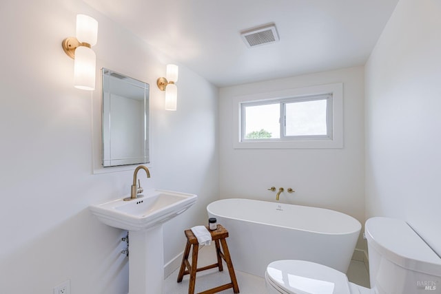 bathroom with baseboards, visible vents, a freestanding bath, and toilet