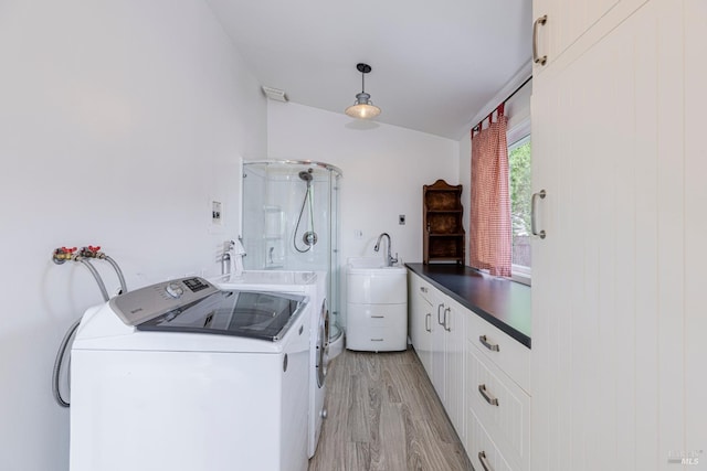 laundry room with visible vents, a sink, washing machine and dryer, cabinet space, and light wood-style flooring