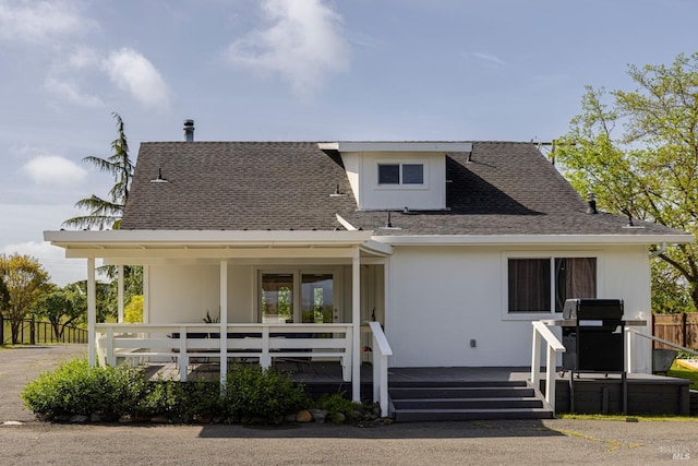bungalow featuring a wooden deck, roof with shingles, and fence