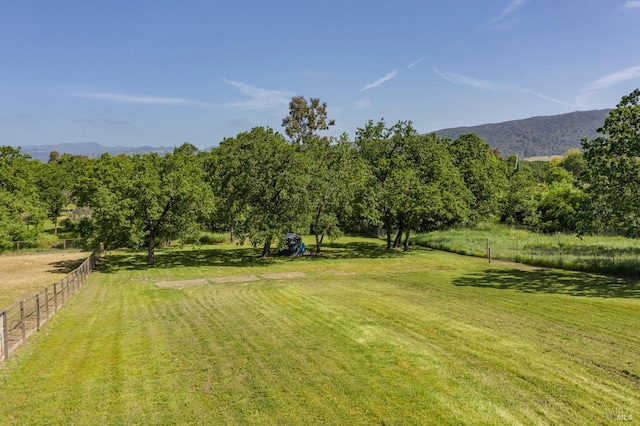 view of yard featuring fence, a rural view, and a mountain view