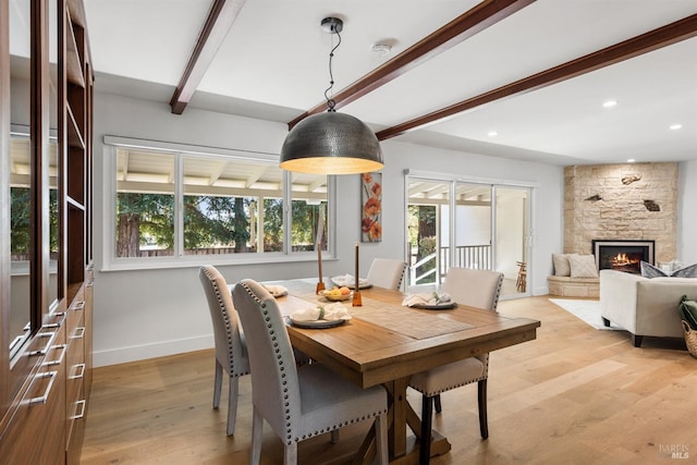 dining room with beamed ceiling, light wood finished floors, a wealth of natural light, and baseboards