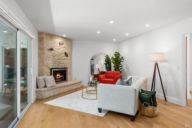 living room featuring recessed lighting, arched walkways, light wood-style flooring, and a fireplace