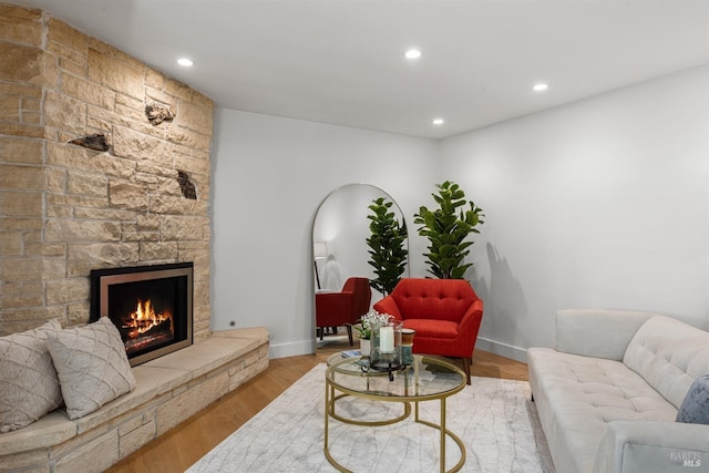 living area featuring baseboards, recessed lighting, wood finished floors, and a fireplace