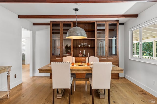 dining room featuring beam ceiling, visible vents, light wood-type flooring, and baseboards