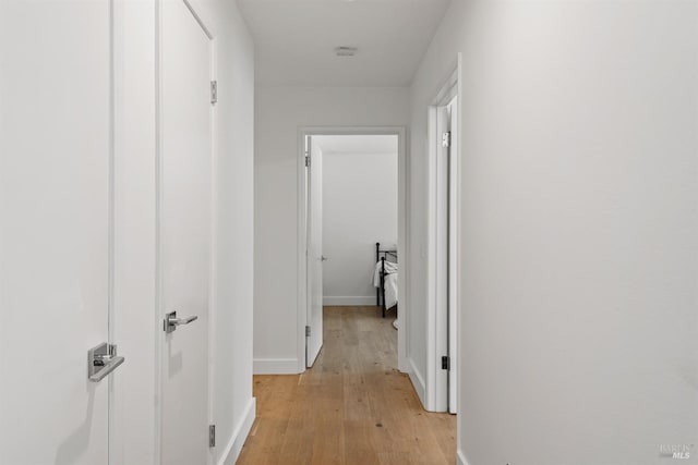 corridor featuring light wood-style flooring and baseboards