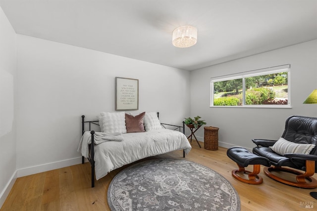 bedroom with a notable chandelier, light wood finished floors, and baseboards