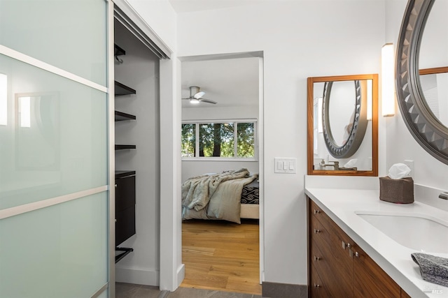 bathroom with ceiling fan, ensuite bathroom, baseboards, wood finished floors, and vanity