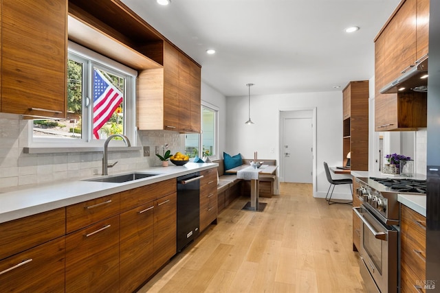 kitchen with black dishwasher, brown cabinets, high end stove, and a sink