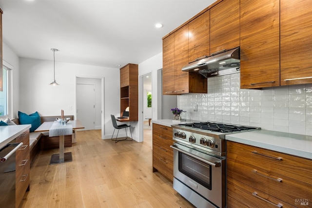 kitchen featuring tasteful backsplash, brown cabinets, stainless steel appliances, and under cabinet range hood