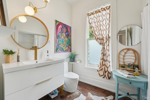 full bath with toilet, baseboards, wood finished floors, and vanity