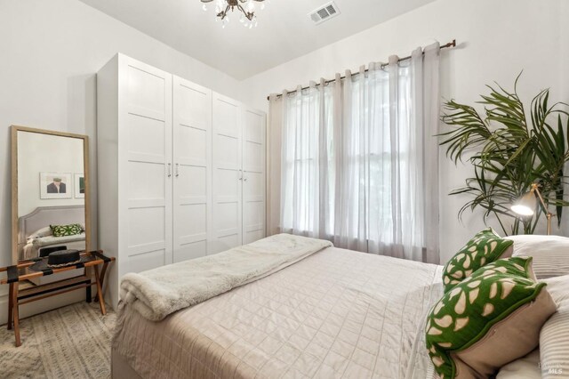 bedroom with a closet, a notable chandelier, and visible vents