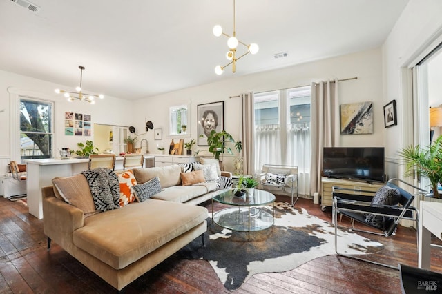living room featuring visible vents, a notable chandelier, hardwood / wood-style flooring, and a healthy amount of sunlight
