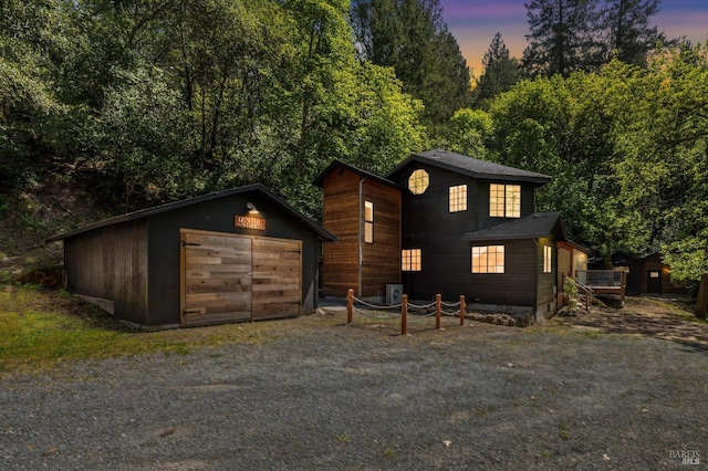 rustic home with driveway, an outdoor structure, and a detached garage