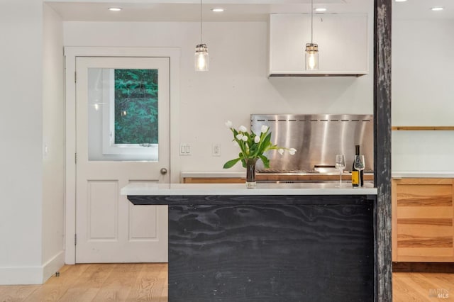 bar featuring decorative light fixtures, light wood finished floors, baseboards, and bar
