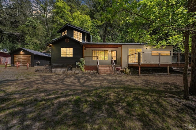 rear view of house featuring an outdoor structure, a garage, a yard, and covered porch